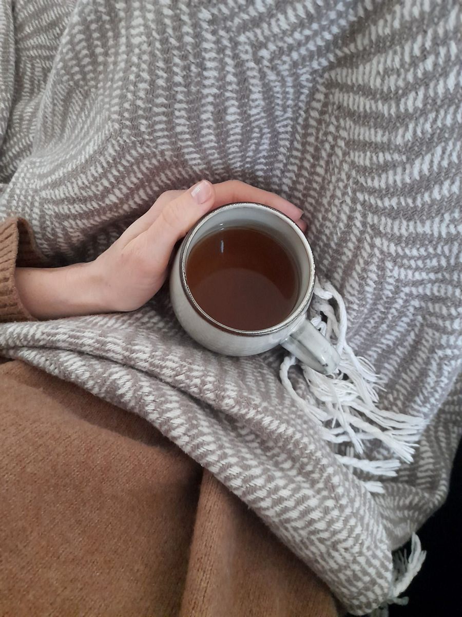 A warm cup of tea wrapped in a cozy blanket